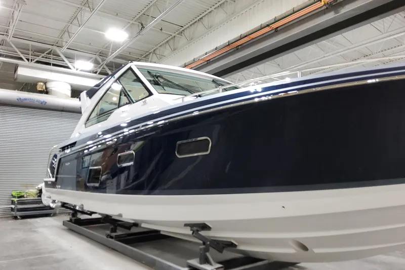Slide: The Image of 2026 Formula 400 Super Sport Crossover boat in a showroom, sleek design, blue and white exterior. - 8