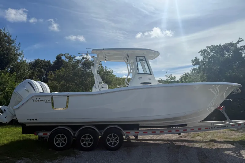 Slide: The Image of 2026 Tidewater 282 CC Adventure boat on trailer under sunny sky. - 14