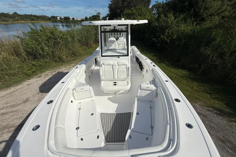 Slide: The Image of 2026 Tidewater 282 CC Adventure boat, spacious deck, white seating, near lush greenery. - 26