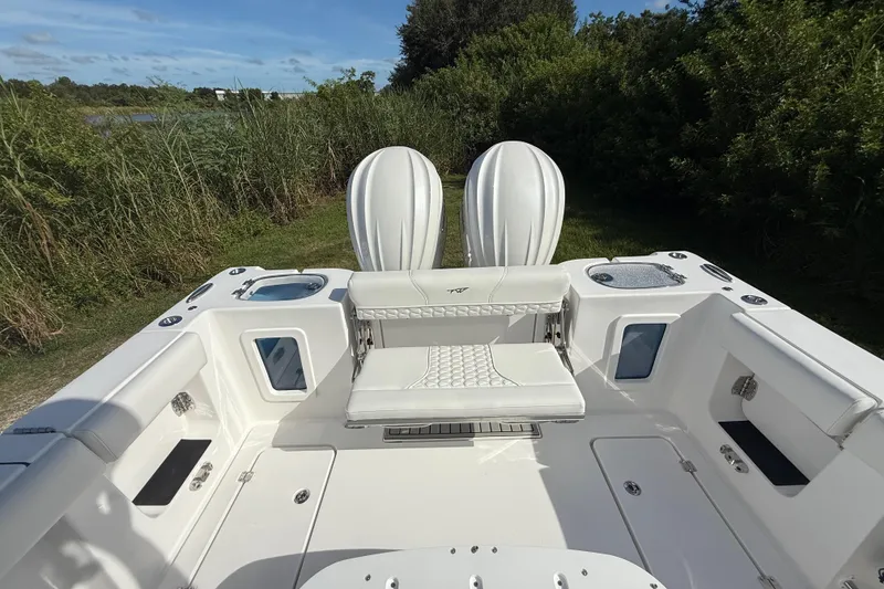 Slide: The Image of 2026 Tidewater 282 CC Adventure boat interior with dual engines, white seating, and lush greenery backdrop. - 31