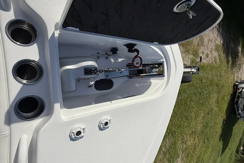 Slide: The Image of 2026 Tidewater 282 CC Adventure boat anchor compartment with cup holders, open hatch, and trailer. - 54