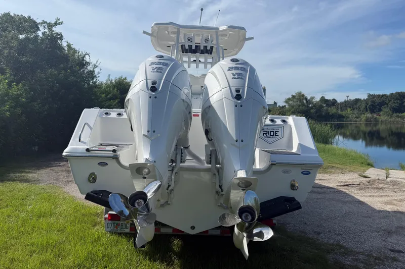 Slide: The Image of 2026 Tidewater 282 CC Adventure boat with dual outboard engines, parked near a serene lake. - 8