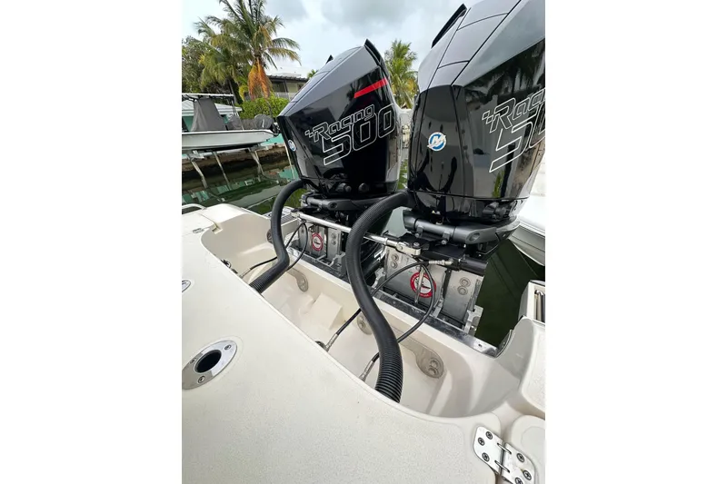 Slide: The Image of Twin outboard engines on a 2021 ShearWater 270 Carolina Flare boat, docked near palm trees. - 28