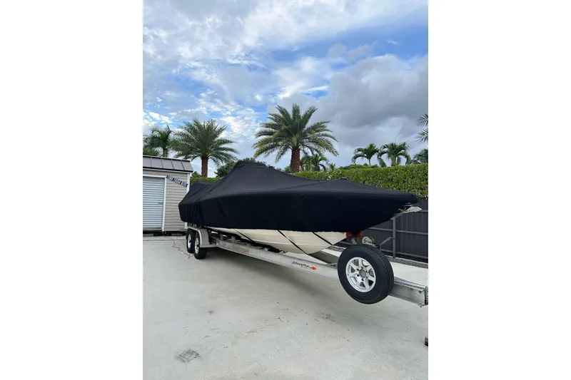 Slide: The Image of 2021 ShearWater 270 Carolina Flare boat covered on trailer, palm trees in background. - 50