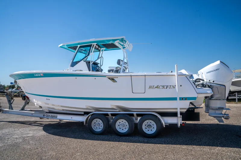 Slide: The Image of 2023 Blackfin 302 CC boat on trailer with Mercury engines, clear blue sky background. - 11