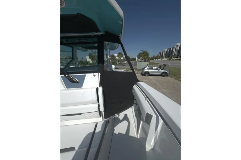 Slide: The Image of 2023 Blackfin 302 CC boat with sleek design, parked near a road with buildings. - 15