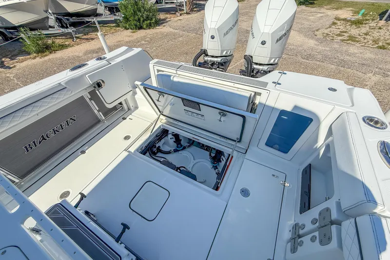 Slide: The Image of 2023 Blackfin 302 CC boat deck with open storage compartment and dual Mercury engines. - 19