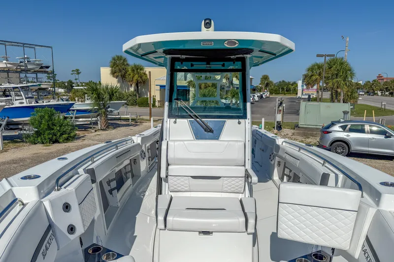 Slide: The Image of 2023 Blackfin 302 CC boat interior with seating and helm, parked outdoors. - 41