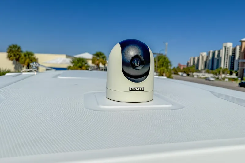 Slide: The Image of 2023 Blackfin 302 CC boat with teal hardtop and rod holders, docked under clear sky. - 54