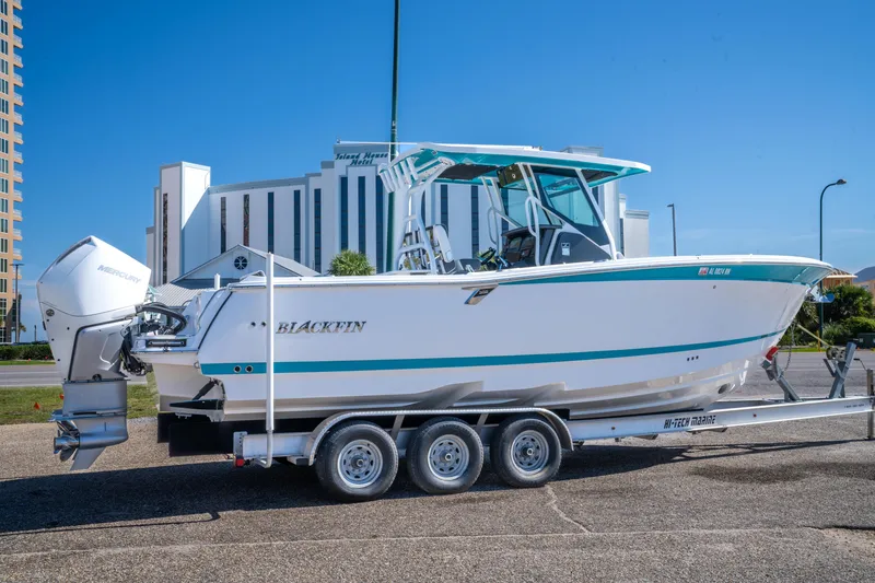 Slide: The Image of 2023 Blackfin 302 CC boat on trailer, parked near modern buildings. - 7
