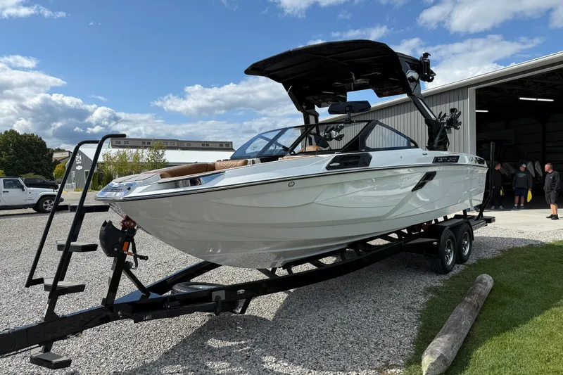 Slide: The Image of 2026 Centurion Ri245 boat on trailer, parked outdoors near a building under a partly cloudy sky. - 6