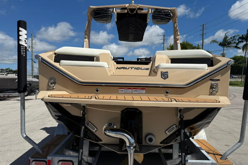 Slide: The Image of 2026 Nautique Super Air Nautique S23 boat rear view on trailer, sunny day. - 5