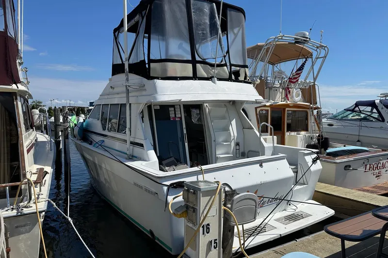 Slide: The Image of 1992 Mainship 35 Convertible docked at marina, featuring spacious deck and flybridge. - 6