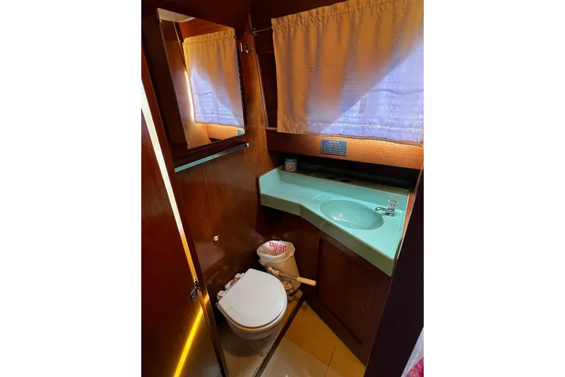 Slide: The Image of 1967 Chris-Craft 31 Commander bathroom with turquoise sink, wooden cabinetry, and curtained window. - 32