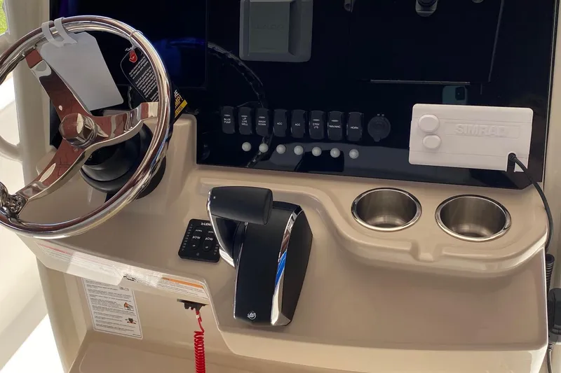 Slide: The Image of 2026 Boston Whaler 220 Dauntless helm with steering wheel, controls, and cup holders. - 10