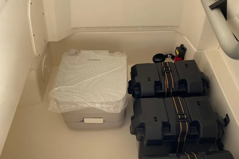 Slide: The Image of 2026 Boston Whaler 220 Dauntless storage area with equipment and battery boxes. - 15