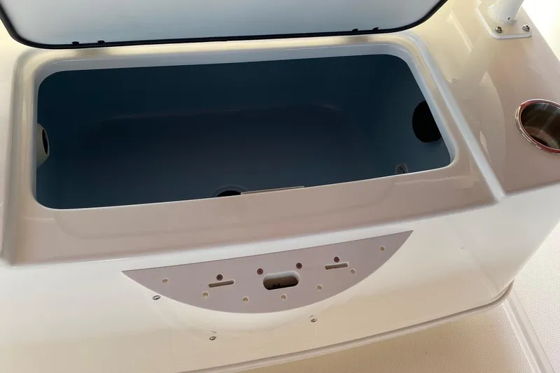 Slide: The Image of 2026 Boston Whaler 220 Dauntless boat storage compartment, open lid, white and blue interior. - 6
