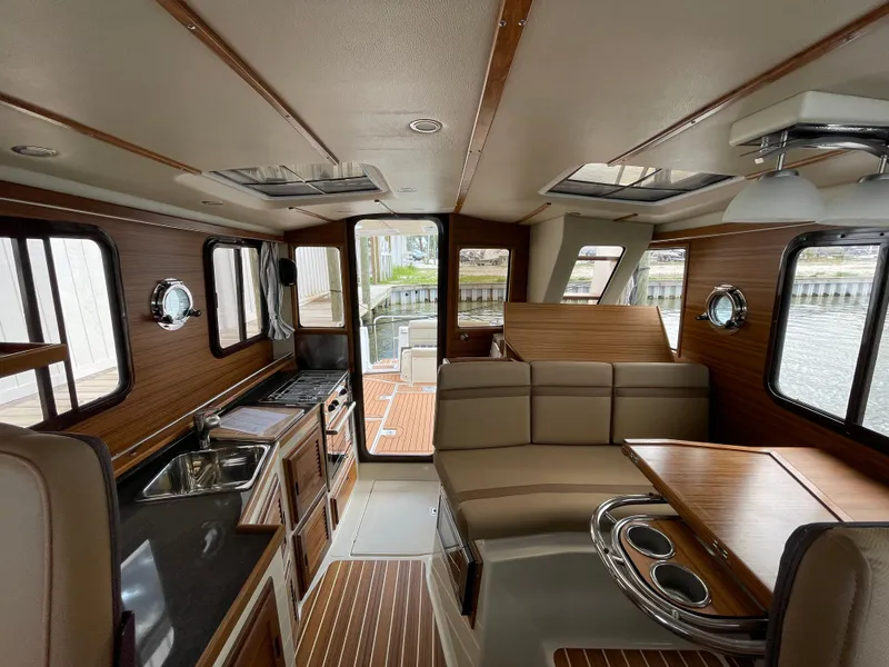 Slide: The Image of 2023 Ranger Tugs R-31 CB interior with wood accents and panoramic windows. - 14