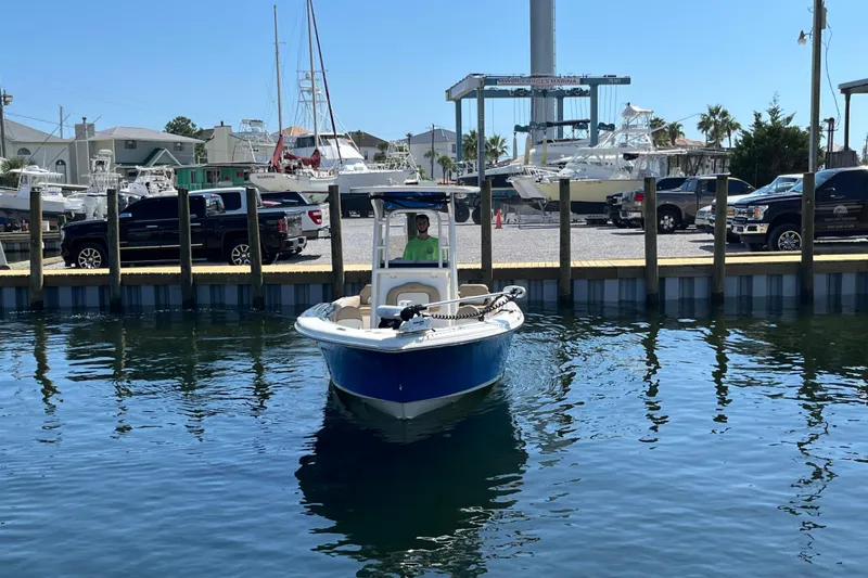Slide: The Image of 2018 Key West 239 FS boat docked at a marina with trucks and yachts in the background. - 2