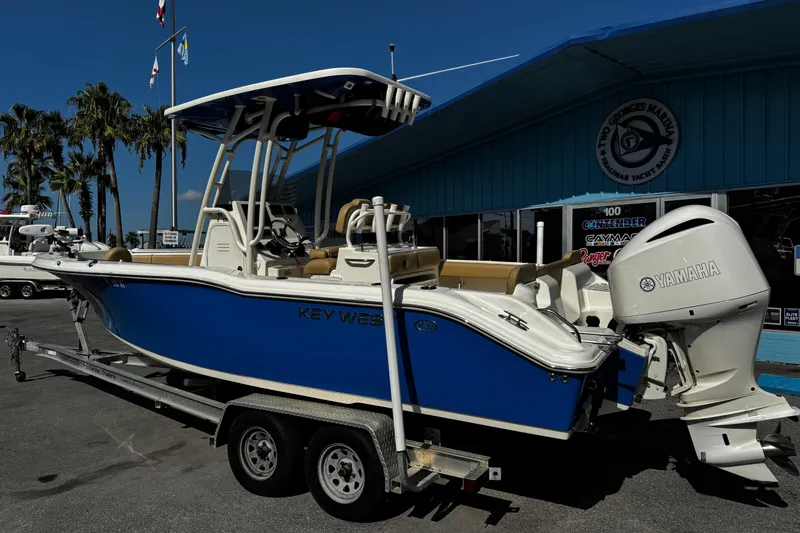 Slide: The Image of 2018 Key West 239 FS boat on trailer, blue hull, Yamaha engine, marina background. - 5