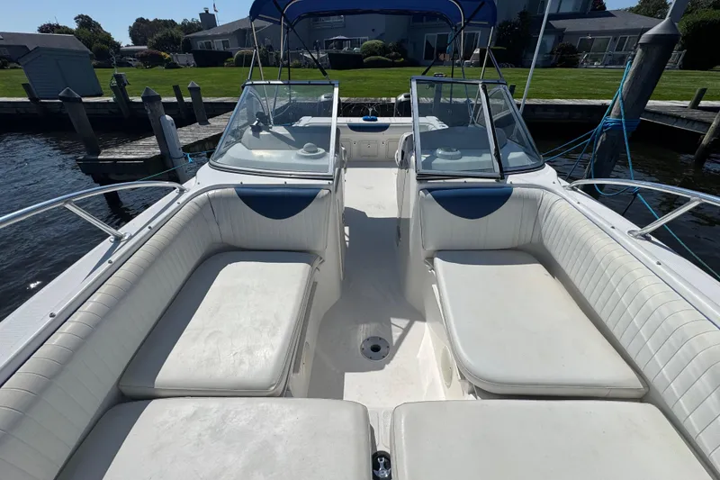 Slide: The Image of 2000 World Cat 246 DC boat interior with white seating, docked by waterfront homes. - 17