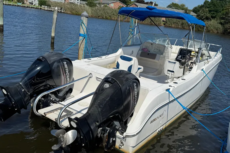 Slide: The Image of World Cat 246 DC 2000 boat with dual Mercury engines docked on calm water. - 4