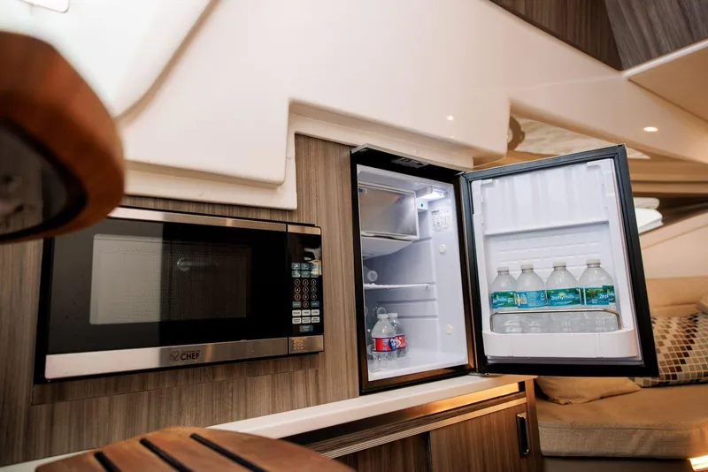 Slide: The Image of 2022 Sea Ray Sundancer 320 Outboard interior with microwave and open mini fridge. - 16