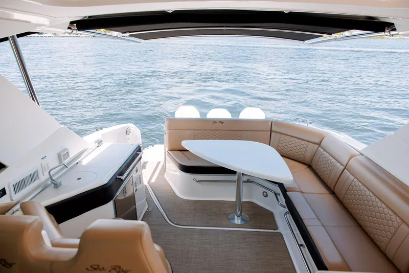 Slide: The Image of 2022 Sea Ray Sundancer 320 Outboard interior with seating and table, overlooking water. - 8