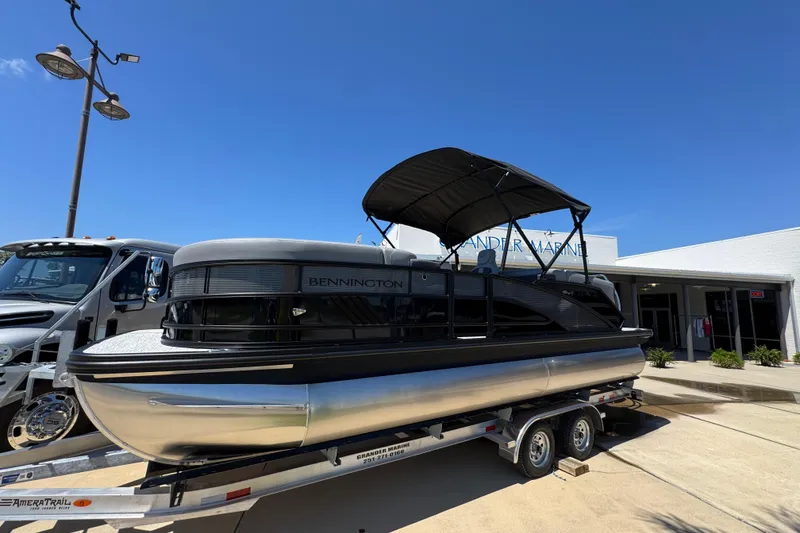 The Image of 2026 Bennington 22 MFB pontoon boat on trailer outside dealership under clear blue sky. - 1