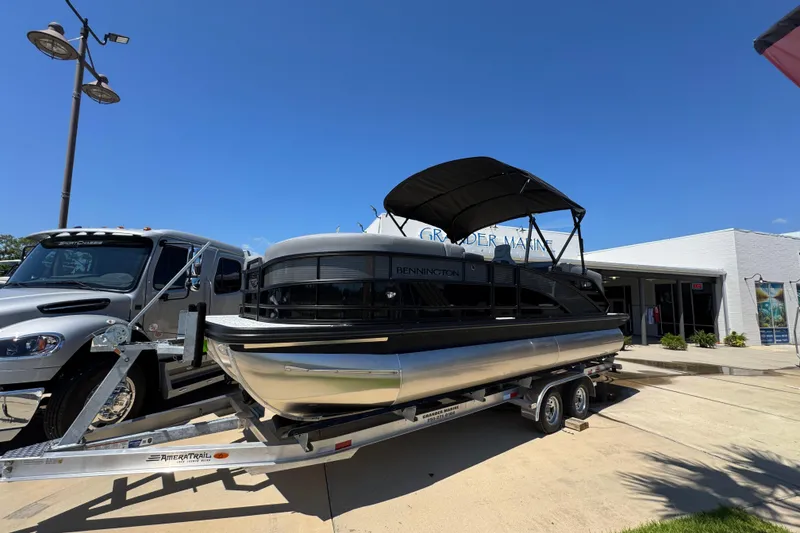 Slide: The Image of 2026 Bennington 22 MFB pontoon boat on trailer outside dealership under clear blue sky. - 2