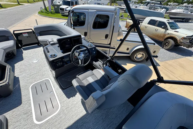 Slide: The Image of 2026 Bennington 22 MFB boat interior with steering wheel and seating, parked near trucks. - 25