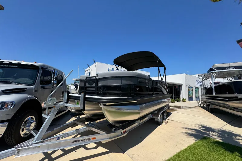 Slide: The Image of 2026 Bennington 22 MFB pontoon boat on trailer, parked outdoors under clear blue sky. - 3