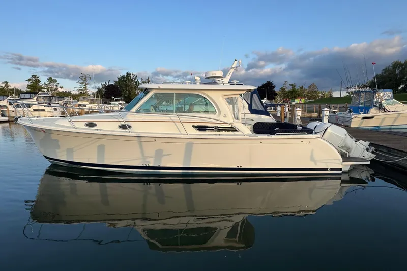The Image of 2020 Back Cove 34O boat docked in a marina, reflecting on calm water. - 0