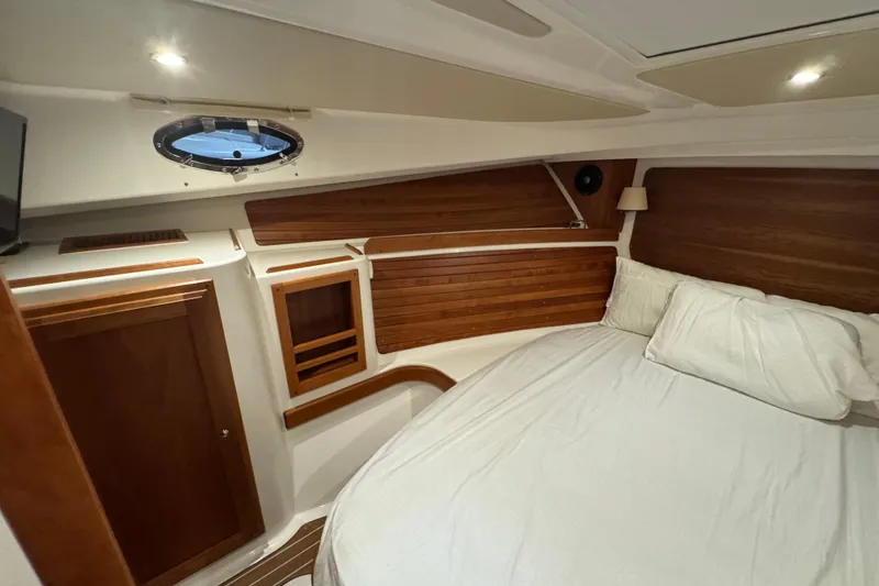 Slide: The Image of 2020 Back Cove 34O cabin interior with wood paneling and cozy bed. - 31
