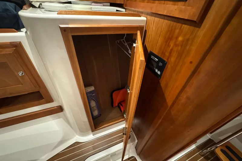 Slide: The Image of 2020 Back Cove 34O interior storage cabinet with wooden finish and open door. - 34