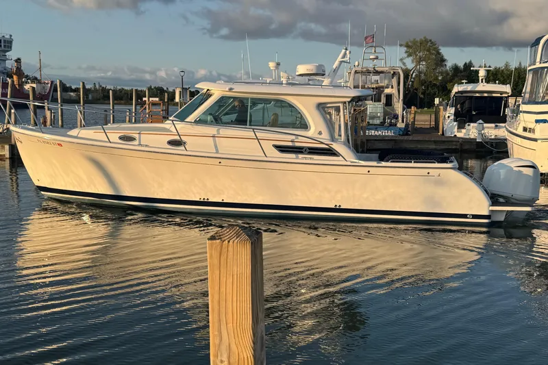 Slide: The Image of 2020 Back Cove 34O boat docked in a marina, reflecting on calm water. - 4