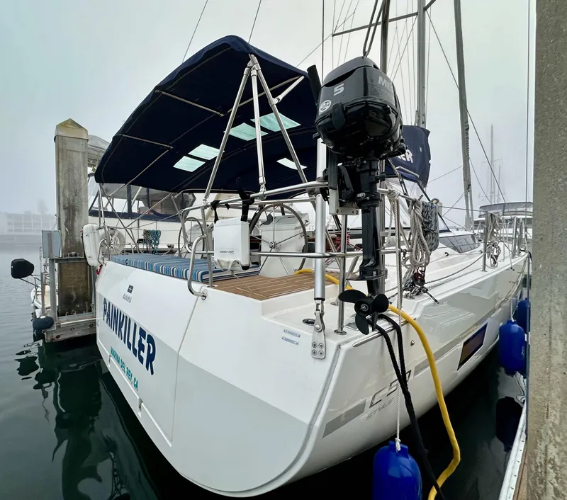 Slide: The Image of 2020 Bavaria C50 sailboat docked, featuring a blue canopy and outboard motor. - 11