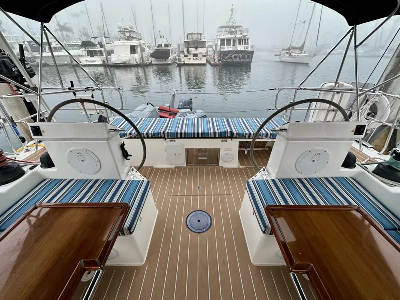 Slide: The Image of Bavaria C50 yacht cockpit with dual steering wheels, striped seating, and marina view. - 25