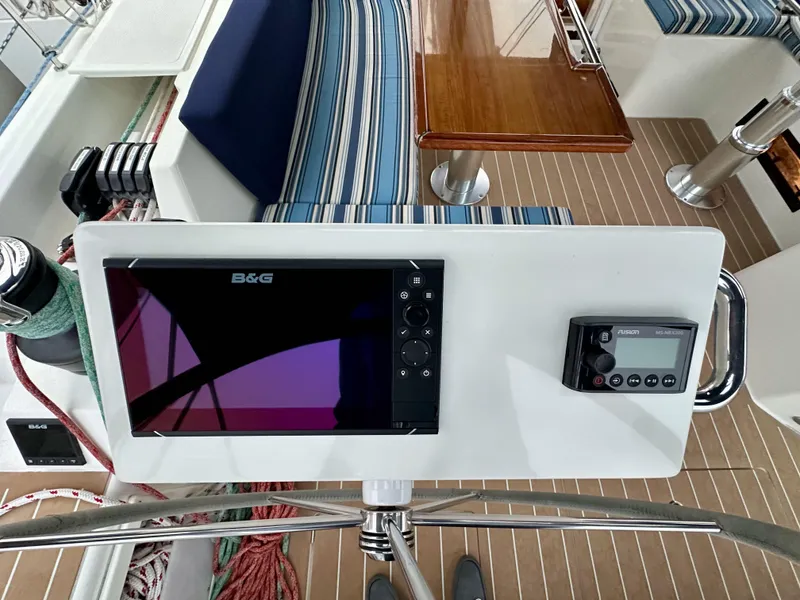 Slide: The Image of Bavaria C50 yacht cockpit with navigation equipment, striped seating, and wooden table, 2020 model. - 27