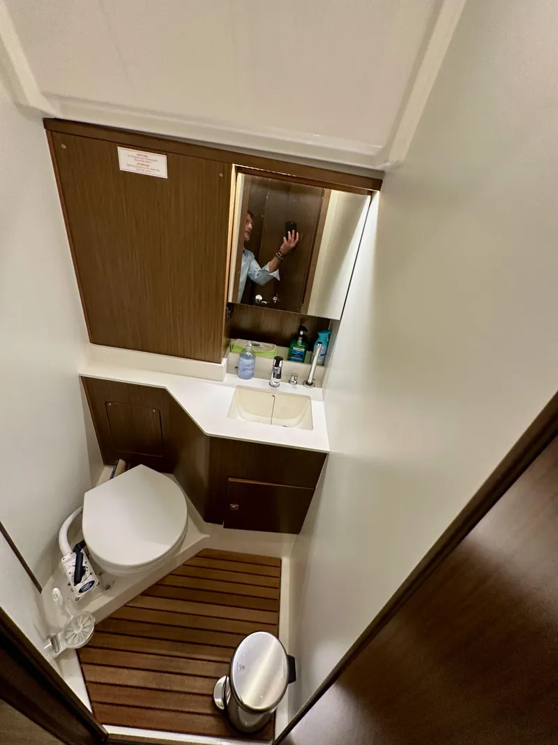 Slide: The Image of 2020 Bavaria C50 yacht bathroom with toilet, sink, mirror, and wooden flooring. - 48