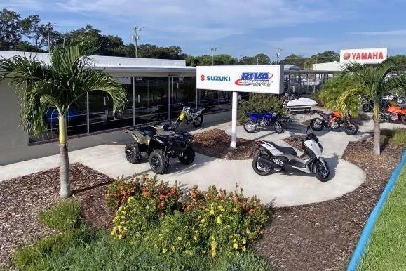 Slide: The Image of Outdoor display of Yamaha and Suzuki vehicles at Riva Motorsports dealership, featuring motorcycles and ATVs. - 24