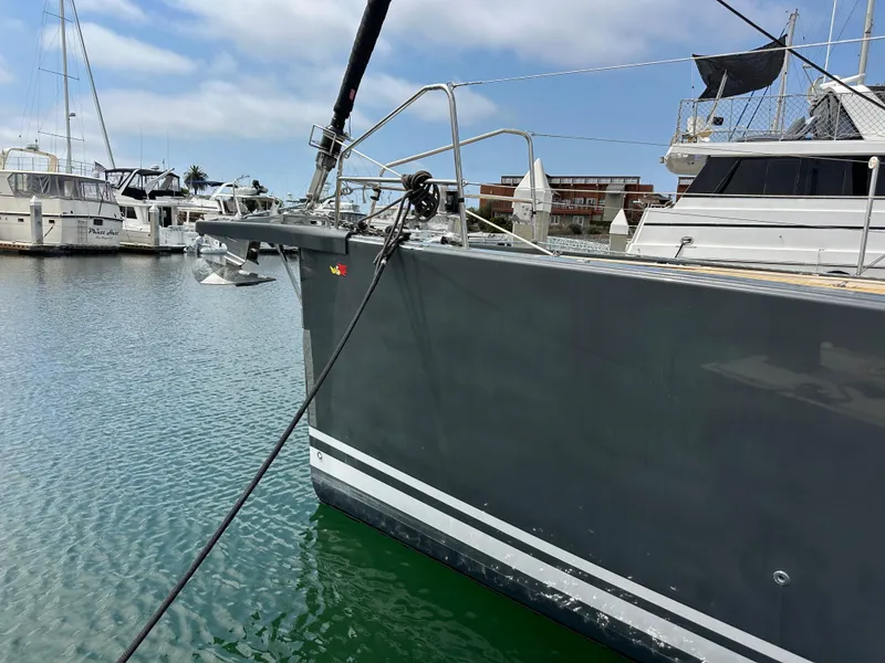 Slide: The Image of 2018 Jeanneau 54 yacht docked in marina, featuring sleek gray hull and anchor. - 14