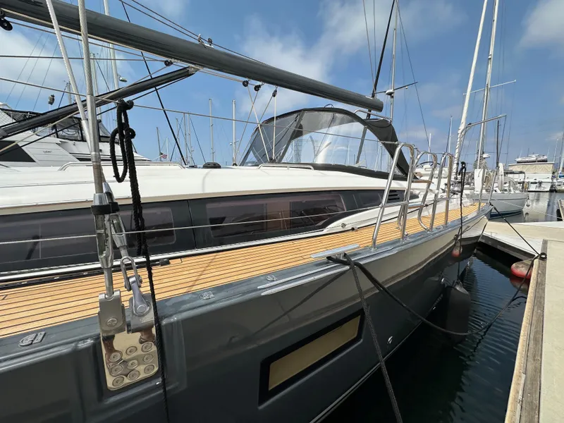 Slide: The Image of 2018 Jeanneau 54 yacht docked at marina, showcasing sleek design and wooden deck. - 18