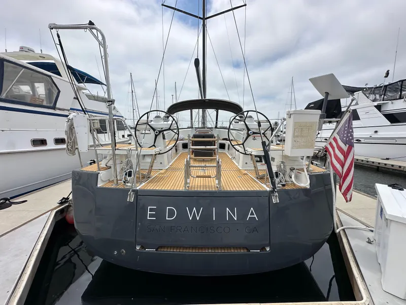 Slide: The Image of 2018 Jeanneau 54 yacht docked, displaying dual steering wheels and American flag. - 23