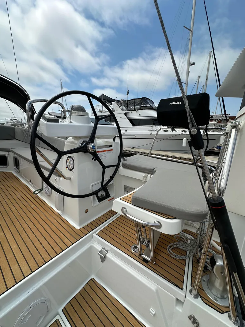 Slide: The Image of 2018 Jeanneau 54 yacht cockpit with steering wheel and teak flooring, docked at marina. - 28