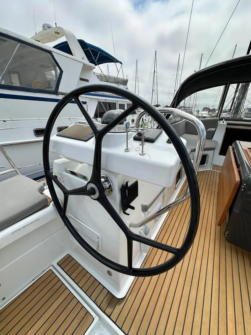 Slide: The Image of Steering wheel of a 2018 Jeanneau 54 yacht with teak deck and marina background. - 29