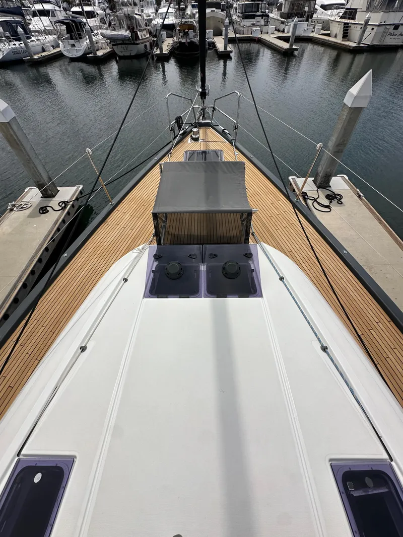 Slide: The Image of Jeanneau 54 yacht, 2018 model, docked at marina with wooden deck and canopy. - 46