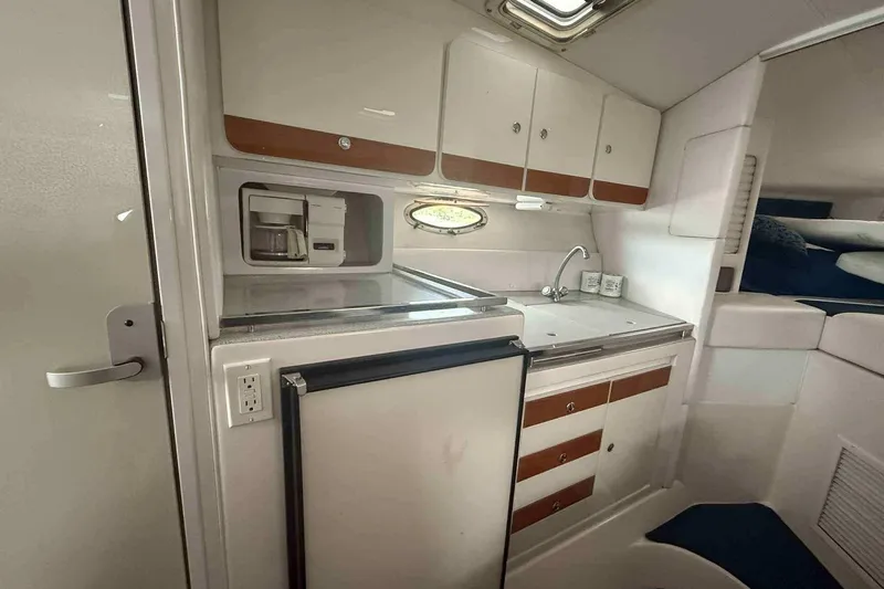 Slide: The Image of 2002 Donzi Z 32 EXPRESS boat interior with kitchenette, featuring cabinets, sink, and coffee maker. - 6