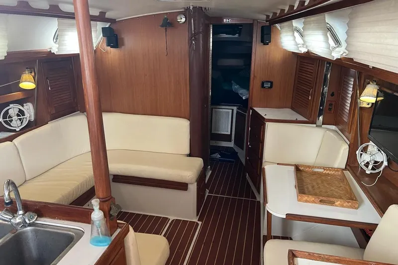 Slide: The Image of Interior of a 1992 Catalina Sloop sailboat with wood paneling and white seating. - 13