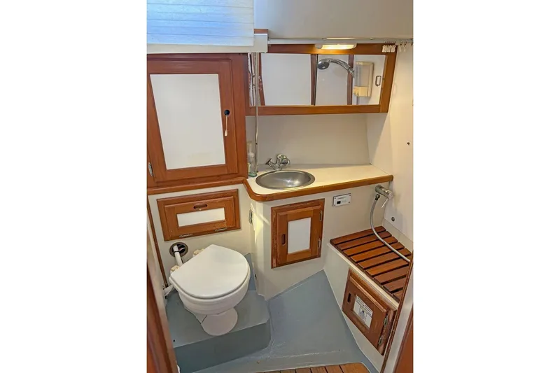 Slide: The Image of 1992 Catalina Sloop bathroom with wooden cabinetry, toilet, sink, and showerhead. - 16